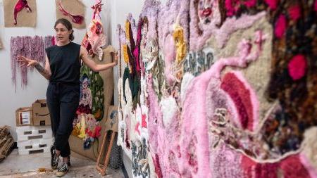 A person standing next to fabric art.